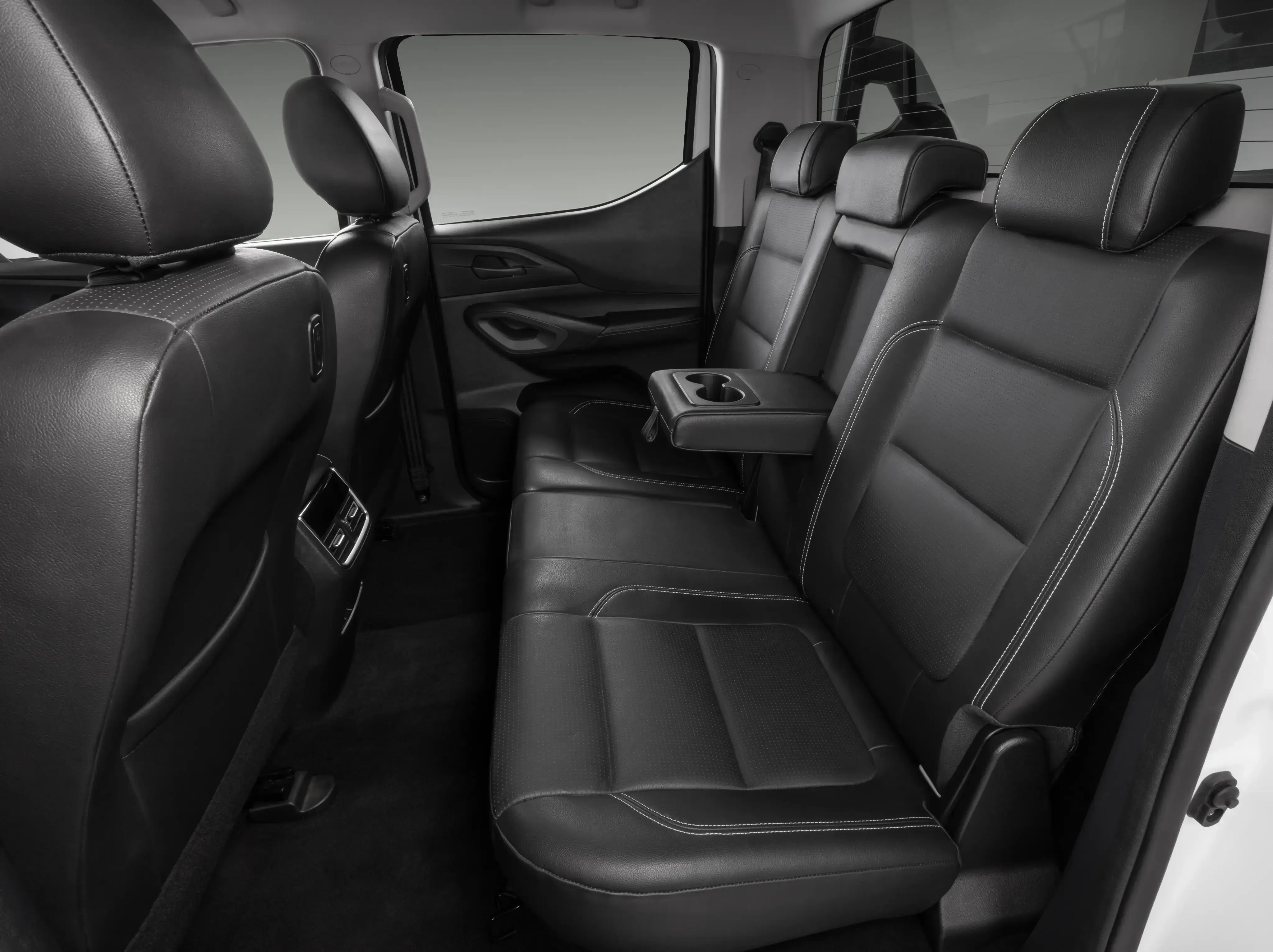 Vista interna de Fiat Titano com destaque para bancos traseiros, com acabamento em couro e porta-copos no encosto rebaixado do assento do meio.